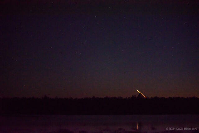Firefly Alpha rises above the trees as seen from Upper Lake Mary near Flagstaff, Arizona. (80mm telephoto)