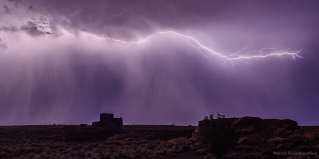 A cloud-to-air lightning flash creates a silhouette of Wukoki Pueblo in Wupatki National Monument.