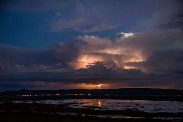 An early evening thunderstorm produces a cloud-to-ground lightning flash with reflections in Mormon Lake.