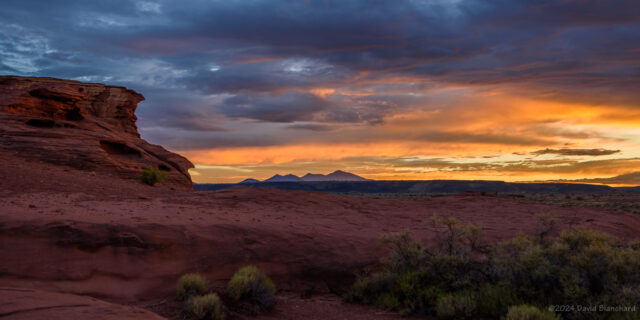 The setting Sun lights up the clouds over the distant San Francisco Peaks.