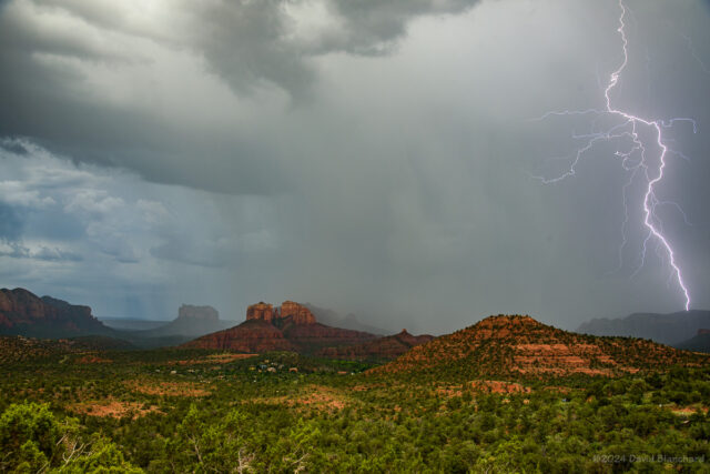 A lightning bolt strikes nearby as heavy rain moves across Cathedral Rock in Sedona.